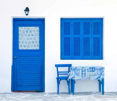 Charming typical floral streets of Greek islands with whitewashed houses and blue doors