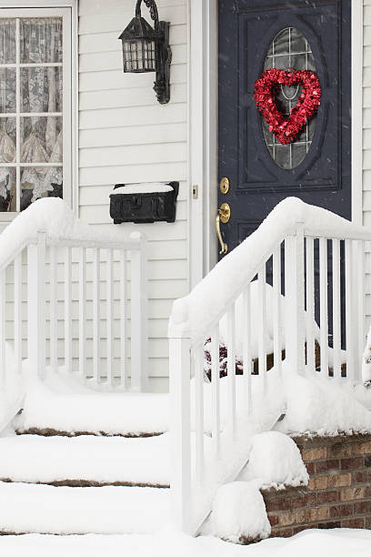 istock February snow on stairway, door has Valentine's Day ornament attached 182519461