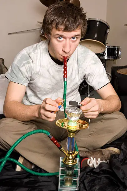 Teenager looks up as he smokes from hookah pipe