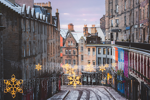 Christmas decorations and the colourful shopfronts of Victoria Street in Edinburgh's old town on a winter morning after a fresh overnight snowfall.
