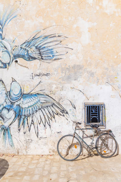 Houmt Souk, Djerba, Medenine, Tunisia. March 16, 2023. Bicycle leaning on a wall with a mural at the Houmt Souk.