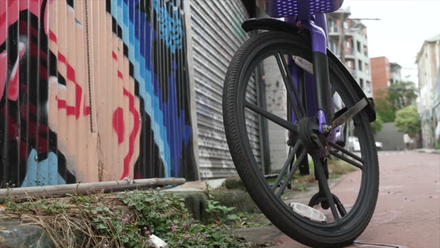 A hire bike stands next to a graffiti'd wall on a quiet urban residential street, innerwest Sydney Australia. close up