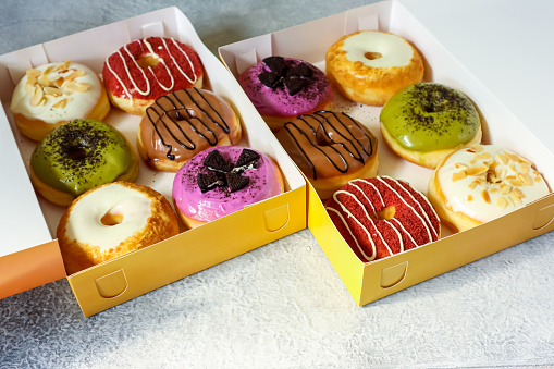 Six assorted sweet donuts in a paper box on the table