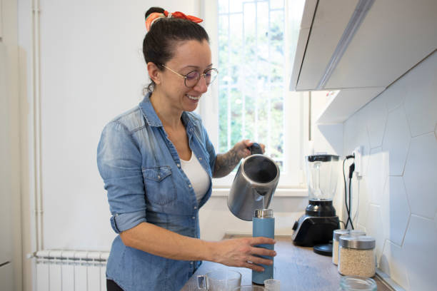 istock Happy, young woman preparing tea at her kitchen. 1825289553