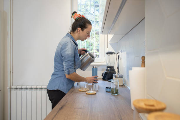 istock Young woman preparing tea at her kitchen. 1825289558