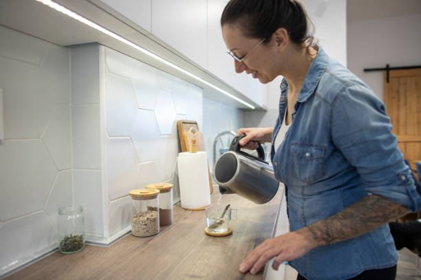 istock Young woman preparing tea at her kitchen. 1825289582