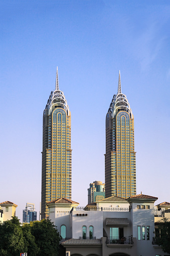 Dubai, UAE - February 23. 2022: The Al Kazim Twin Towers agaist blue sunny sky. Al Kazim Towers is a complex of two towers in Dubai Media City, resembling New York City's Chrysler Building