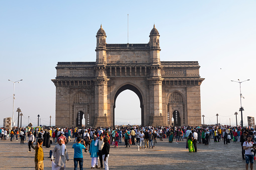 21st January, 2020 - Mumbai, India: This editorial image captures the bustling scene at the Gateway of India, one of Mumbai's most iconic and historically significant landmarks. Situated on the waterfront, the grand archway serves as a focal point for both locals and tourists alike. In the photograph, a diverse mix of people can be seen - local residents enjoying their city's heritage, visitors taking in the monument's architectural beauty, and tourists capturing memories against its majestic backdrop. The Gateway, with its Indo-Saracenic design, stands as a testament to Mumbai's colonial past and its transition into a modern metropolis. The image aims to showcase the lively atmosphere of this popular spot, highlighting its role as a cultural and social hub in the heart of Mumbai.
