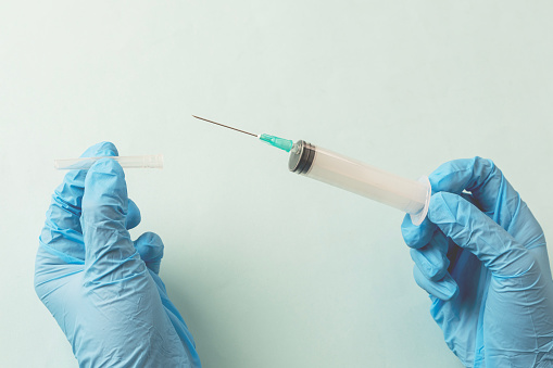 Doctor is holding a syringe , isolated on blue background