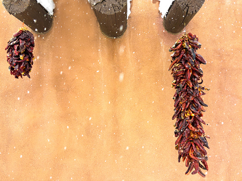 Santa Fe, NM: Adobe wall and two ristras in a snows. Copy space available.