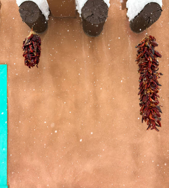 Santa Fe, NM: Adobe wall and two ristras in a snows. Copy space available.