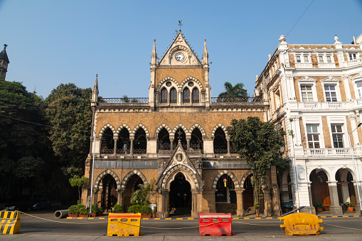 This image captures the essence of Kala Ghoda, a vibrant cultural precinct in Mumbai known for its rich artistic and architectural heritage. Kala Ghoda, which translates to 'Black Horse', is characterized by its array of heritage buildings, art galleries, boutiques, and cafes, all contributing to its distinctive charm. The photograph highlights the eclectic mix of neo-Gothic and art deco styles that define the area's architecture, set against the backdrop of contemporary urban life. This district is a hub for creative and cultural activities, hosting various events including the famous Kala Ghoda Arts Festival. The image aims to convey the unique blend of history, art, and culture that makes Kala Ghoda a must-visit destination for anyone exploring the diverse tapestry of Mumbai.