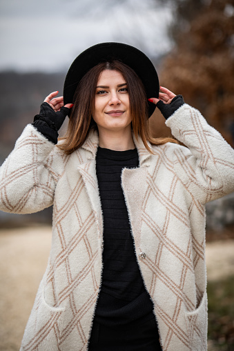 Portrait of a beautiful cheerful girl in a white sweater, in nature, looking at the camera