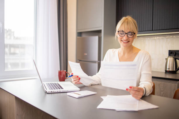 istock Mature woman using calculator while going through bills and home finances 1825501378