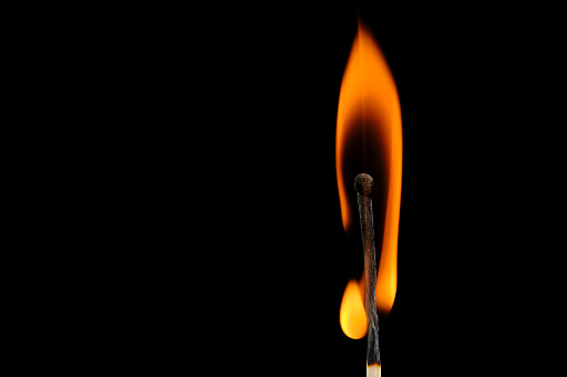 A yellow and orange  flame coming from an ignited wood match. Blue background ... Copy space on the flame.