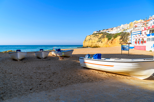 Boats sit on the sandy Praia de Carvoeiro Beach at the village of Carvoeiro, a small fishing town along the sea in the Algarve region of Southern Portugal. Carvoeiro is a town and a former civil parish in the municipality of Lagoa, Algarve, Portugal. In 2013, the parish merged into the new parish Lagoa e Carvoeiro. The population in 2011 was 2,721, in an area of 11.66 km². It is located about 5 kilometres south of Lagoa or Lagos.