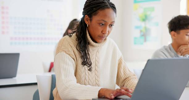 istock Girl, students and laptop in a classroom, knowledge and creativity with connection, typing and learning. African person, academic and pc with kids, studying and education with lessons and high school 1825633755