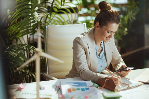 istock smiling woman employee in green office using phone 1825634302