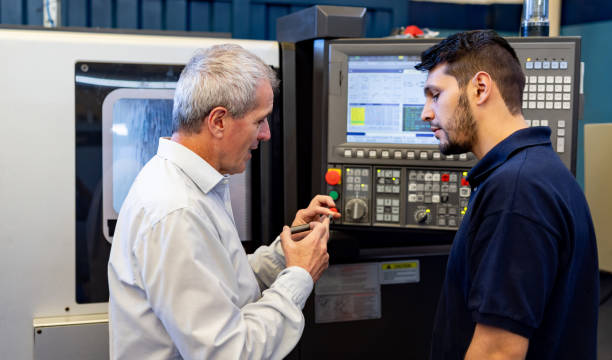 istock Foreperson training an employee on how to use a thread making machine on a screw 1825645466