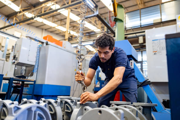 Employee working at a factory and moving heavy pieces with the help of a machine Latin American employee working at a factory and moving heavy pieces with the help of a machine manufacturing occupation stock pictures, royalty-free photos & images