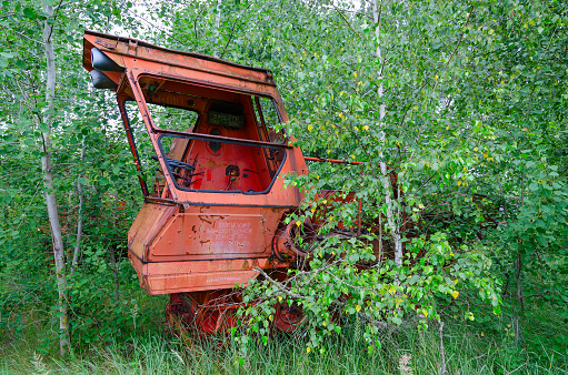 Abandoned combine harvester in former mechanized yard of state farm Victory of Socialism in resettled village of Pogonnoye in Chernobyl exclusion zone, Belarus. Inscription on harvester: Crew No. 2 We undertake to harvest 160 hectares and thresh 450 tons