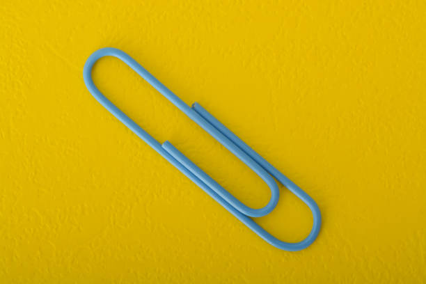 istock Blue paper clip isolated on a yellow background. 1825778994