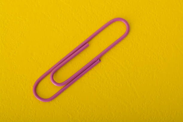 istock Purple paper clip isolated on a yellow background. 1825779521