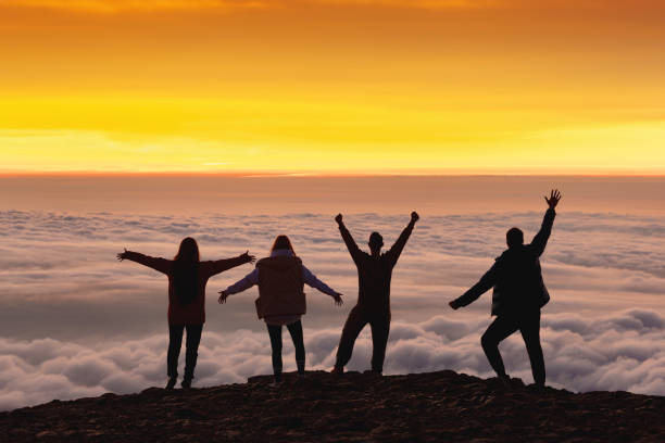 istock Happy friends greeting sunrise above the clouds 1825872922