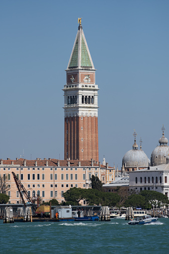 tall brick bell tower with bright blue sky at the famous St.Mark square in Venice, Italy