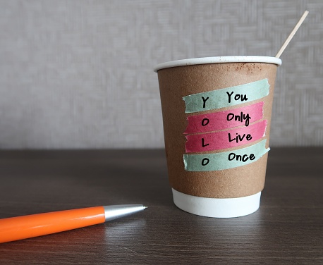 Coffee cup with text written You Only Live Once - concept of YOLO - ideology is an encouragement to seize the day, to go for it, live your best life now