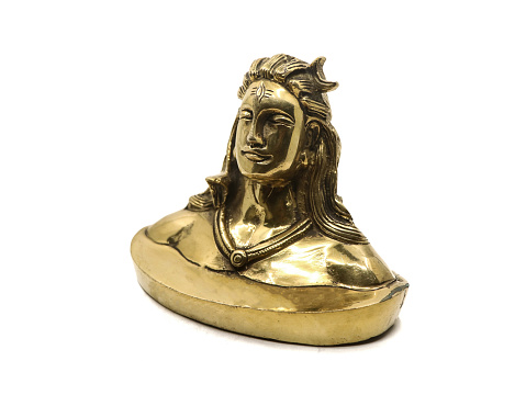 shiny golden idol of lord shiva of hindu religion, antique replica model handcrafted in brass based on adiyogi statue, for car dashboard isolated in a white background