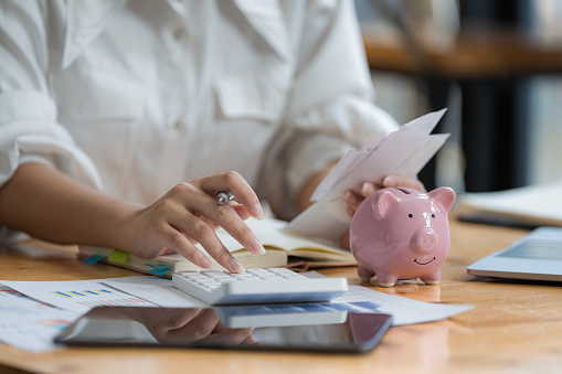 Close-up portrait of businesswoman accountant using calculator and laptop for matching financial data saving in office room, Business financial, tax, accounting concept.