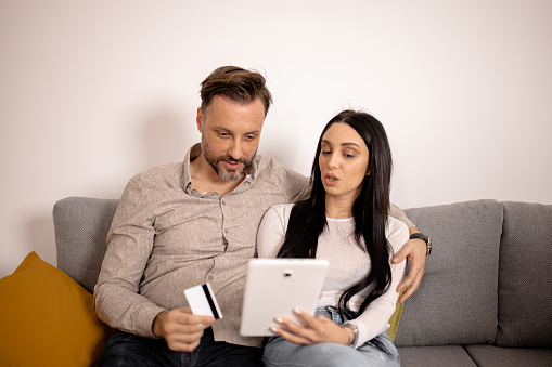 This young couple is making the most of their sofa time by sharing a digital experience together through their digital tablet