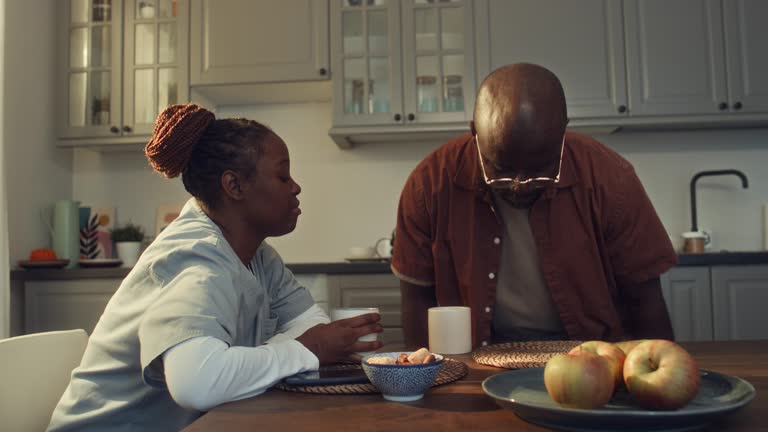 Black Wife in Nurse Uniform and Husband Chatting in Morning over Coffee