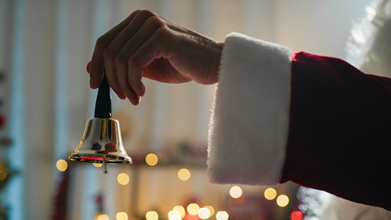 Santa ringing a small bell with his hand.