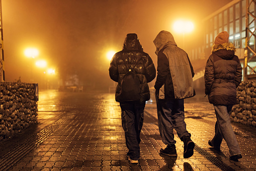 Teenagers walking in the Štrbské Pleso train station on a foggy night\nShot with Canon R5