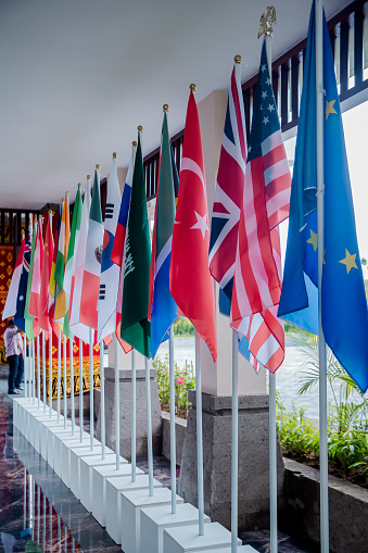 National flags of different countries indoors during government meeting, forum, conference summit or other international event