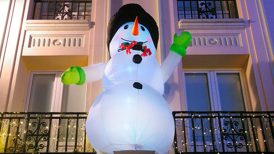 Inflatable large snowman hanging from cast iron balconies,  hat and carrot nose, Lugo city Chistmas decorations, Galicia, Spain.