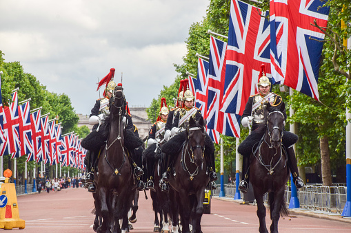 London, UK - June 1 2022: Members of the Household Cavalry Mounted Regiment on horses pass through The Mall lined with Union Jacks.