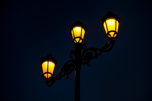 Close-up of an old street lamp with mosquitoes at night.