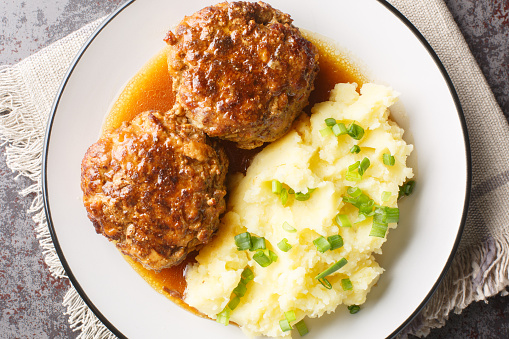 Delicious large meatballs with gravy with a side dish of mashed potatoes close-up in a plate on the table. Horizontal top view from above