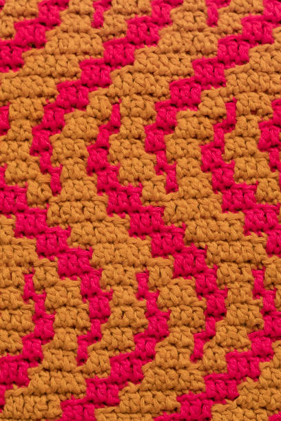 istock Yellow pink crochet mosaic fabric with wavy pattern close up. Knitted background. 1826381767