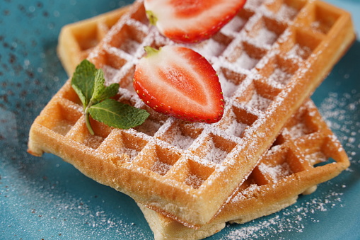 Belgian waffles with fresh strawberries, sugar powder and mint leaves