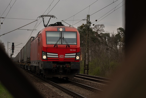 Darmstadt, Germany – April 06, 2023: A vibrant red passenger train traveling along a scenic railway route in Germany.