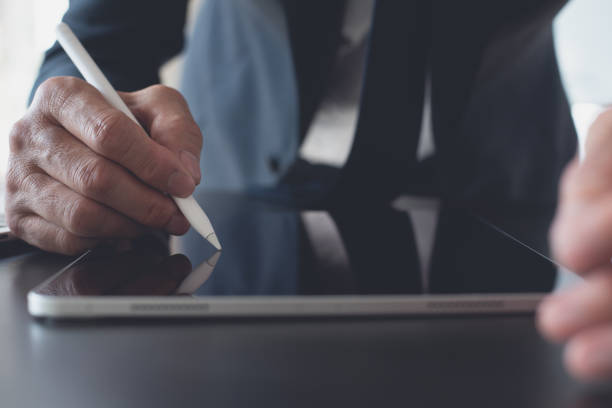 istock Businessman hand using stylus pen touching on digital tablet screen with laptop computer on office table. Business man signing e-document on tablet, online working at office, close up 1826429017