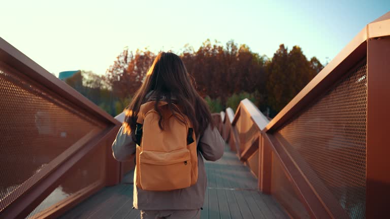 Young woman with backpack is walking on a bridge