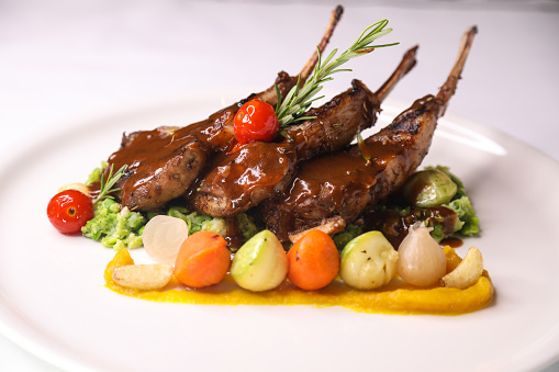 NEWZELAND LAMB CHOPS or mutton CHOP with tomato, onion and potato served in dish isolated on table closeup side view of arabian food