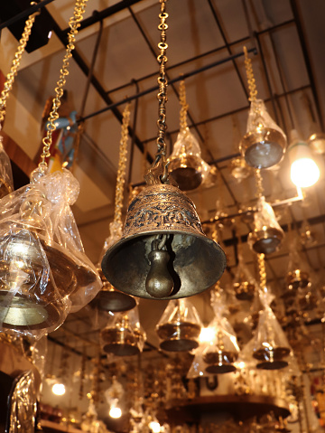 decorative brass bell hanging on a chain inside a antique shop selling handcrafted objects in the market near the temple