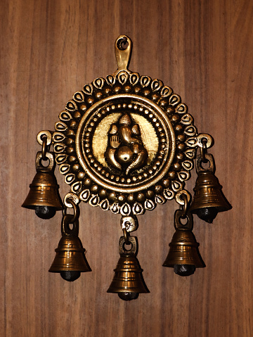 old antique bronze bells with a decorative ganesh statue on a wooden wall
