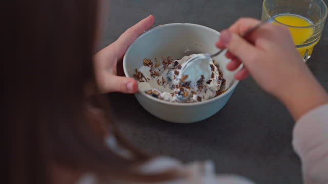 Caucasian Girl Mixing Cereals and Fruits with Yogurt